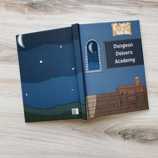 Hardcover journal open showing both covers, the back a starry night sky over rolling hills, the front a moonlit classroom scene with a chalkboard reading "Dungeon Delvers Academy," a treasure map, and a desk with an iced drink, on a wood surface.