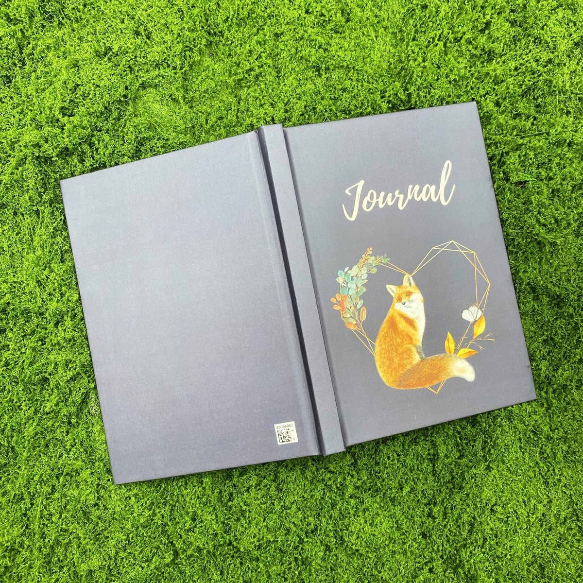 Open navy hardcover journal showing the blank back cover and the fox and heart wreath design on the front cover.