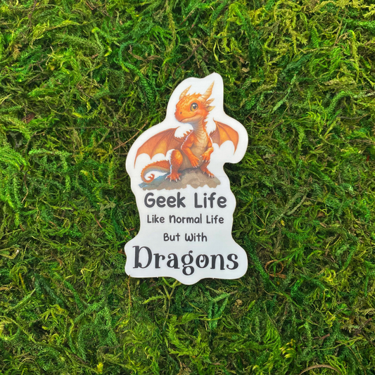 A sticker illustration of a baby orange dragon perched on a rock above the text "Geek Life. Like normal life but with Dragons," resting on artificial moss.