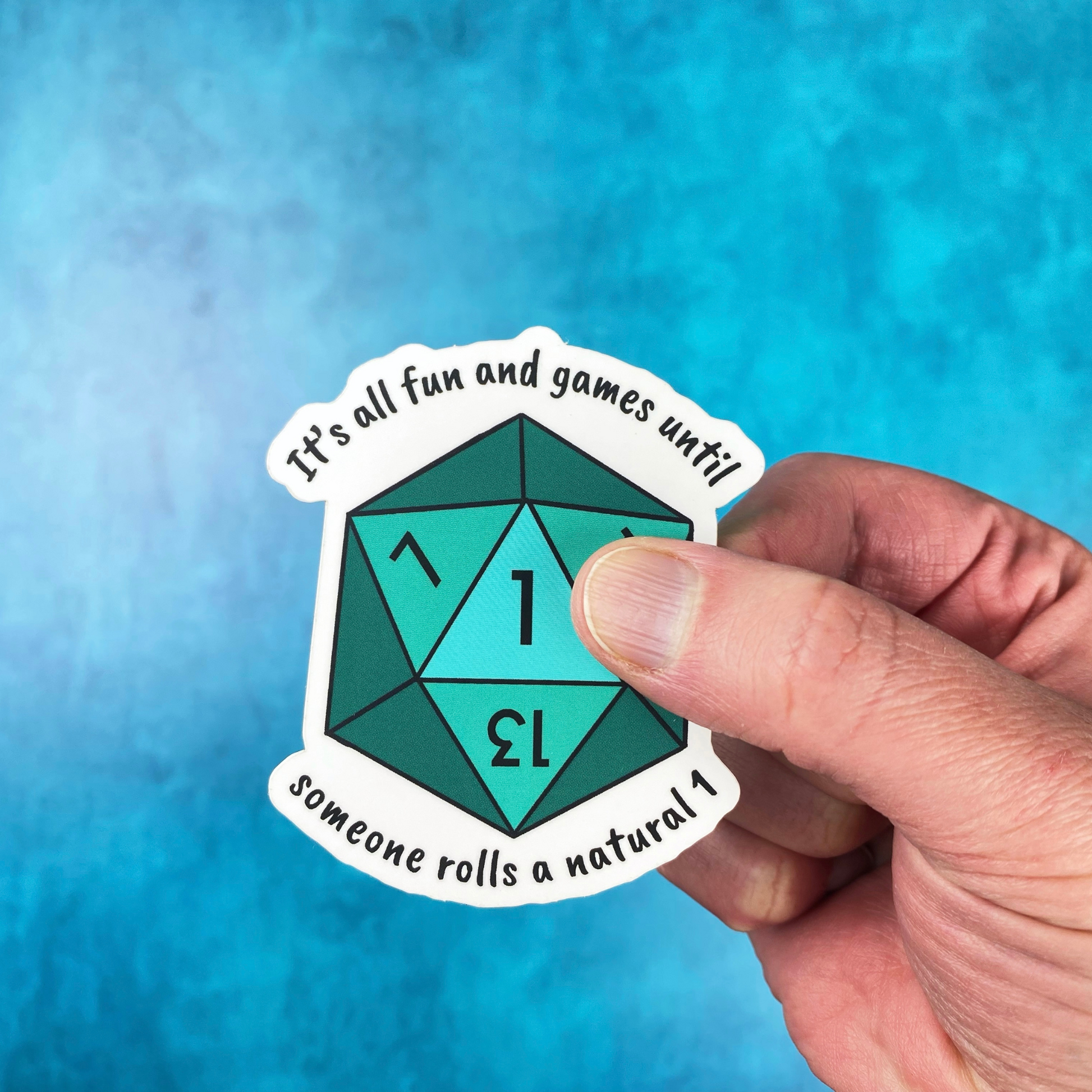 Die-cut vinyl sticker showing a teal d20 die, with the text "It's all fun and games until someone rolls a natural 1," on a teal background