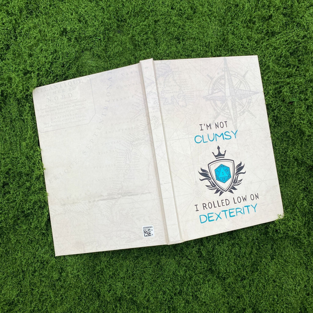 Open hardcover journal showing the vintage map print on both the front and back covers, with the 'I'm not clumsy, I rolled low on dexterity' design on the front.