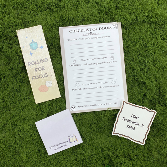 A curated gift set on artificial grass featuring a "Checklist of Doom" notepad with Summon, Sacrifice, and Survive sections, a "Rolling for Focus" bookmark with a teal d20, a sticky note reading "Schedule? I thought you said ritual," and a parchment-style sticker reading "I Cast Productivity...It Failed."