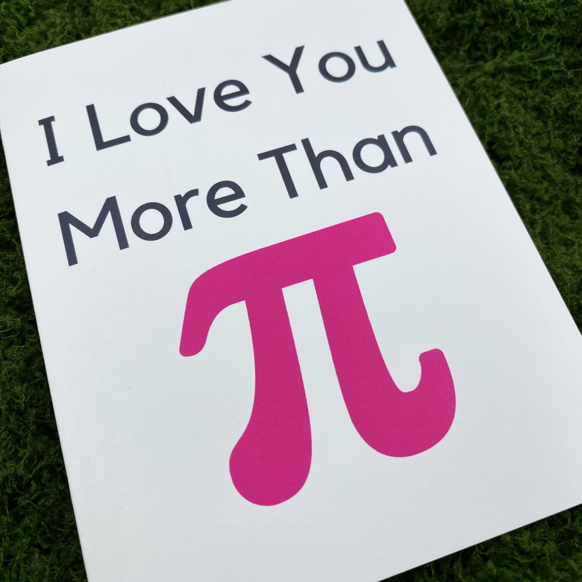 Close-up of the card's cover showing "I Love You More Than" in black text above a large pink pi symbol.