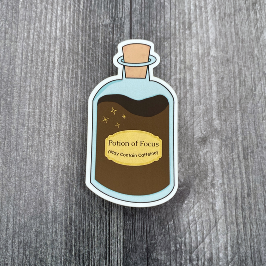 Die-cut vinyl sticker showing a corked potion bottle labeled "Potion of Focus (May Contain Caffeine)," on a gray wood background