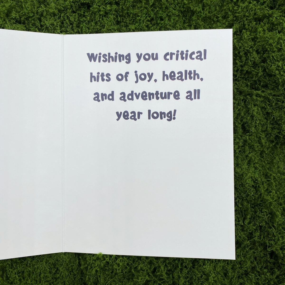 Open interior of the greeting card showing the printed message "Wishing you critical hits of joy, health, and adventure all year long!"